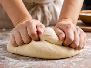 Kneading smooth and elastic doughnut dough on a floured surface