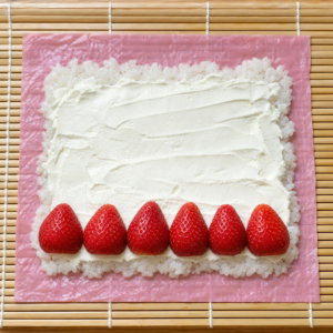 Cream cheese filling spread over rice with a row of fresh strawberries